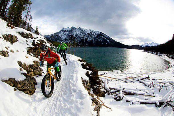 two cyclists riding mountain bikes in snow 