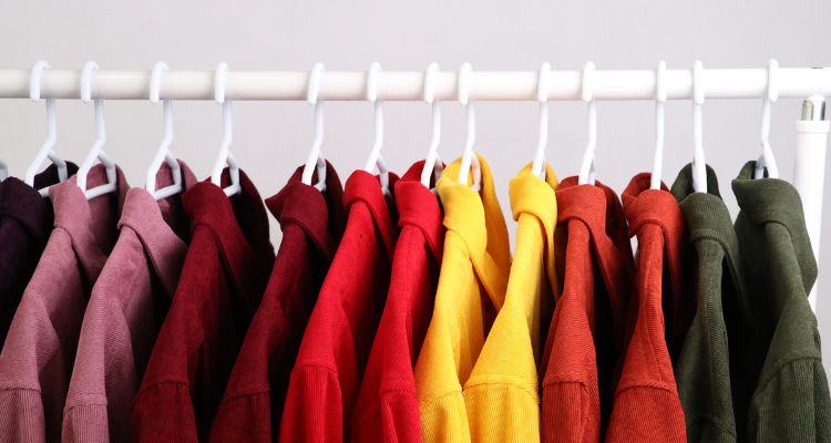 Clothes with complementary colors hanging side by side on a clothing rack